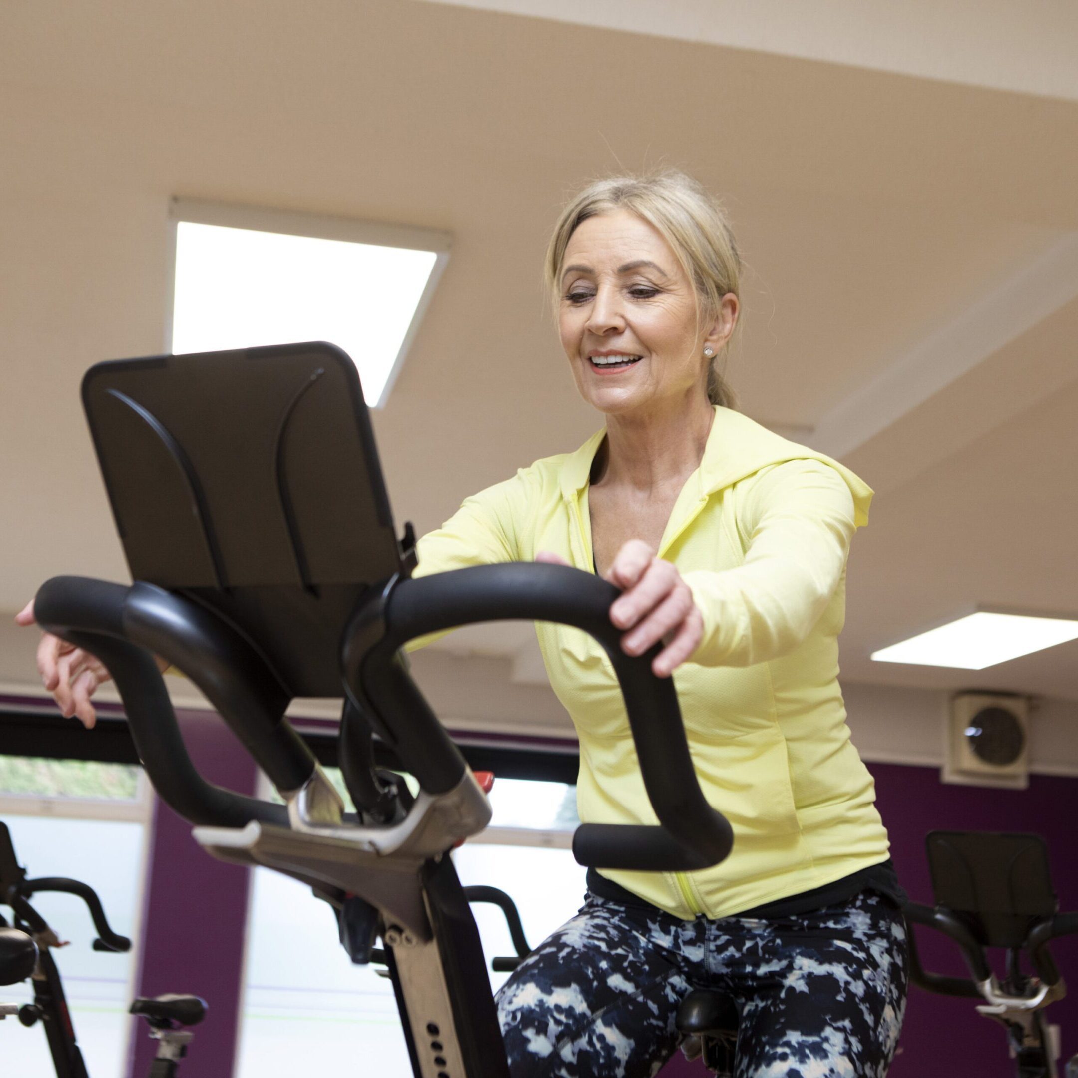 Woman using an exercise bike in a gym A woman is riding an exercise bike in the gym.